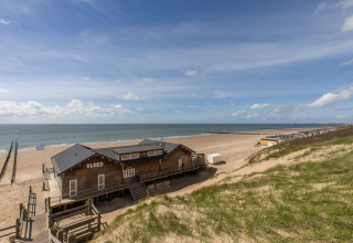 Udsigt over en strandhytte ved Strand Dishoek 342 i Zeeland, Holland, med klitter og hav i baggrunden.
