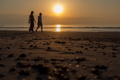 Dos personas caminan por la playa al atardecer cerca de la cabaña Strand Dishoek 342 en Welcome In, Zeeland, Países Bajos.