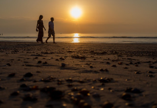 Deux personnes marchent sur la plage au coucher du soleil près du Strand Dishoek 342 à Welcome In, Zeeland, Pays-Bas.