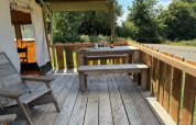 Terrasse en bois avec table et bancs d’un safari-tente au Domaine Le Faulion en France, en plein été.