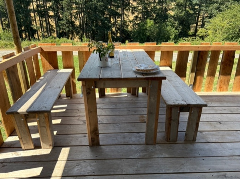 Udendørs træbord og bænke på en terrasse med udsigt til skov, taget ved safari telt på Domaine Le Faulion.