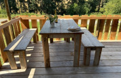 Table et bancs rustiques en bois sur une terrasse, vue sur la forêt, au Safari tent du Domaine Le Faulion, France.