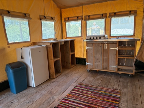 Interior de una tienda safari en Domaine Le Faulion, Francia, con encimeras de madera, nevera y estufa.
