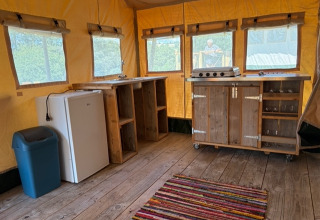 Interior of a safari tent at Domaine Le Faulion in France with wooden counters, fridge, and stove.