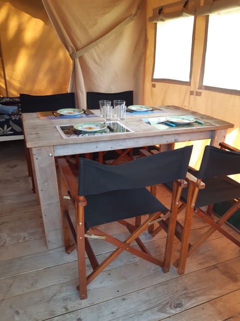 Holztisch und Stühle im Safarizelt auf Domaine Le Faulion in Frankreich, gedeckt für vier Personen.