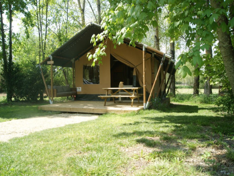 Tienda safari 'WOOD' en el Camping des Tourbières, Francia, con terraza, mesa y entorno natural verde.