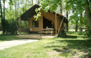 Safari tent 'WOOD' at Campsite des Tourbières in France, with a porch, picnic table and green scenery.