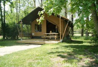 Tienda safari 'WOOD' en el Camping des Tourbières, Francia, con terraza, mesa y entorno natural verde.