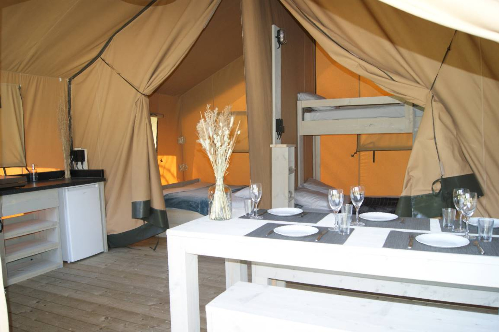 Binnenaanzicht van de safaritent 'WOOD' op Camping des Tourbières in Frankrijk met eettafel en bedden.
