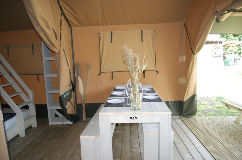 Interior of the Safari tent «WOOD» at Campsite des Tourbières in France, with dining table and benches.