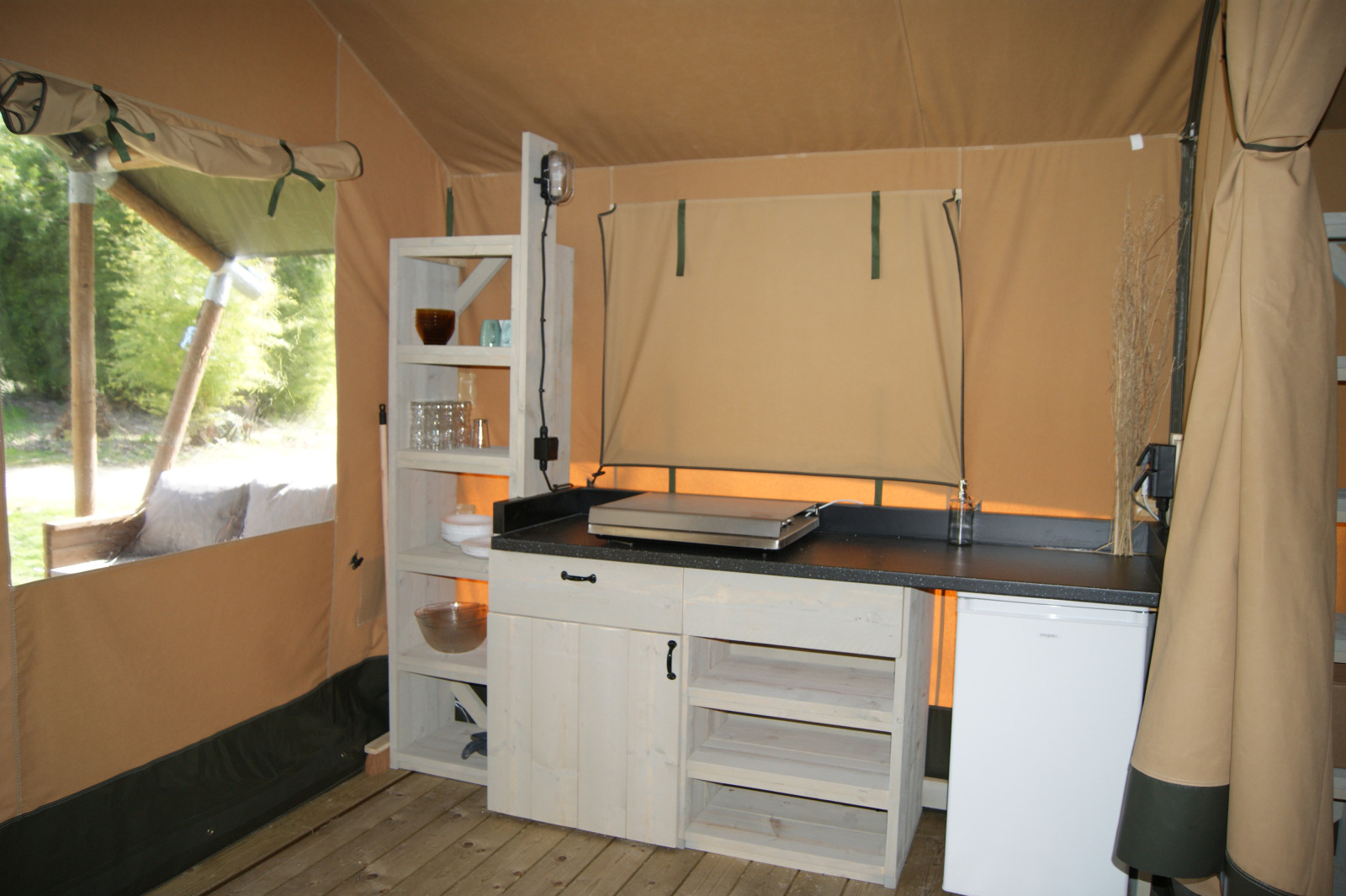 Keukengedeelte in safaritent 'WOOD' op Camping des Tourbières in Frankrijk met rekken en koelkast.