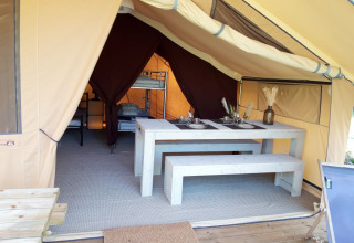 Innenraum eines Safarizeltes auf dem Campingplatz des Tourbières in Frankreich mit Esstisch und Betten.