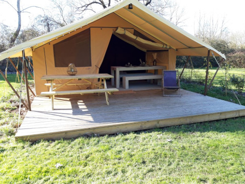 Safari-Zelt auf dem Campingplatz des Tourbières in Frankreich mit Holzterrasse und Sitzgelegenheiten.