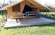 Safari tent at Campsite des Tourbières in France with wooden deck, picnic table, and outdoor chair.