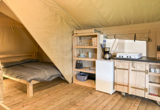 Interior de una tienda safari con cama doble y cocina en el Camping des Randonneurs en Francia.