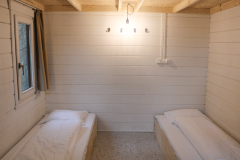 Twee enkele bedden in een gerenoveerde basis cabine met witte houten muren bij Urban-Gardens Gent.