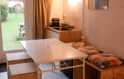 Gerenoveerde basic cabin in Gent, België, met eettafel, keukenhoek en uitzicht op de groene tuin.