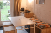 Renoveret basic cabin i Gent, Belgien, med lille spisebord, bænk, køkken og udsigt til grøn have.
