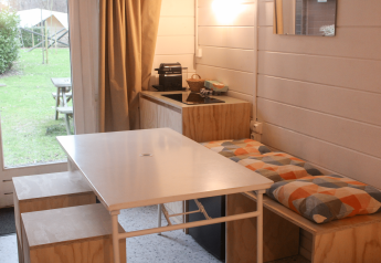 Cabaña básica renovada en Gante, Bélgica, con mesa de comedor, cocina y vista al jardín exterior.