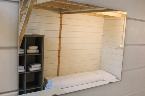 Interieur van een gerenoveerde tiny cabin met bed, vide en handdoekenrek bij Urban-Gardens Gent, België.