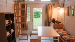 Interior of the renovated Basic cabin tiny house in Gent, featuring kitchen, table, loft and bench.
