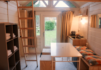 Interieur van de gerenoveerde Basic cabin tiny house in Gent met keuken, tafel en loftladder.