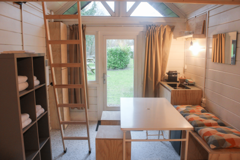 Binnenkant van de gerenoveerde Basic cabin tiny house in Gent met keuken, tafel en ladder.