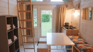 Interior de la tiny house renovada 'Basic cabin' en Gante con cocina, mesa y escalera al altillo.