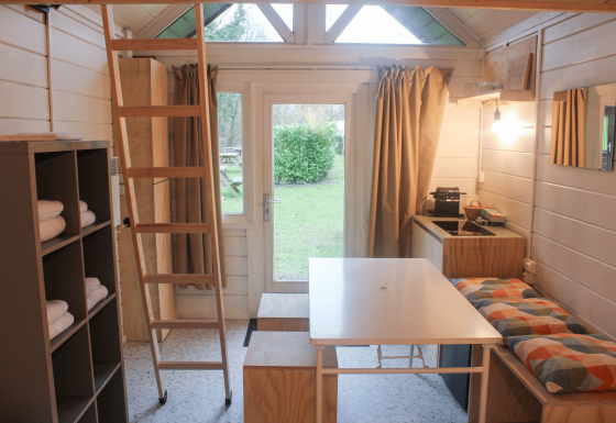 Interieur van de gerenoveerde Basic cabin tiny house in Gent met keuken, tafel en loftladder.