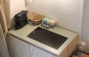 Piccolo angolo cottura con macchina da caffè, cestino, tovaglioli e piano a induzione in una cabina rinnovata a Gent.