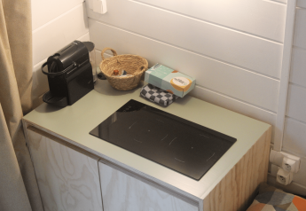Kleine Küchenzeile mit Kaffeemaschine, Korb, Servietten und Induktionskochfeld in renovierter Hütte in Gent.