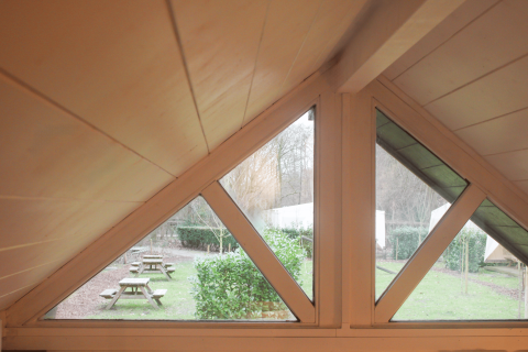 Uitzicht vanuit het driehoekige raam van de gerenoveerde Basic Cabin bij Urban-Gardens Gent, België.