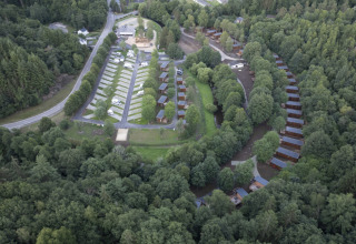 Luftaufnahme vom Ferienpark Le Hameau de l'Ourthe in Belgien mit Chalets, Wohnmobilen und viel Wald.
