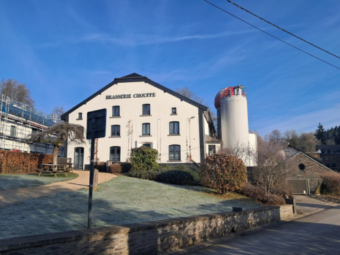 Le bâtiment Brasserie Chouffe au parc de vacances Le Hameau de l'Ourthe, entouré de nature et sous ciel bleu en Belgique.