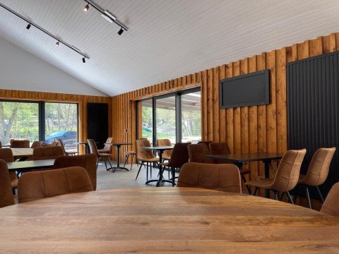 Indretning af en moderne spisehal med træpaneler og store vinduer i Le Hameau de l'Ourthe, Belgien.