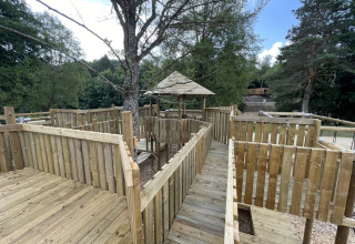 Parque infantil de madera con pasarelas y barandillas en un entorno boscoso en Le Hameau de l'Ourthe, Bélgica.