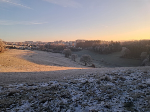 Sonnenaufgang über einer frostigen Landschaft bei Le Hameau de l'Ourthe, Provinz Luxemburg, Belgien.