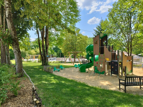 Parco giochi con scivolo e altalene tra alberi al Campeggio des Tourbières in Nouvelle-Aquitaine, Francia.