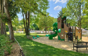 Playground with slide, swings and trees at Campsite des Tourbières in Nouvelle-Aquitaine, France, on a sunny day.