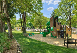 Parco giochi con scivolo e altalene tra alberi al Campeggio des Tourbières in Nouvelle-Aquitaine, Francia.