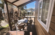 Terraza cubierta con mesa y cuatro sillas en la cabaña Bungalow «Confort Poniente» en TAIGA Conil, España.