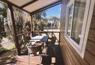 Terraza cubierta con mesa y cuatro sillas en la cabaña Bungalow «Confort Poniente» en TAIGA Conil, España.