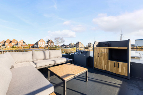 Udendørs siddeområde på Houseboats «Lemmer» ved Marina Lemmer, med sofa, bord og udsigt i Holland.