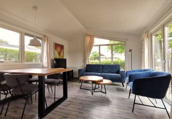 Lyst opholdsområde i Chalet Basic på De Woudhoeve, Holland, med moderne møbler og store vinduer.