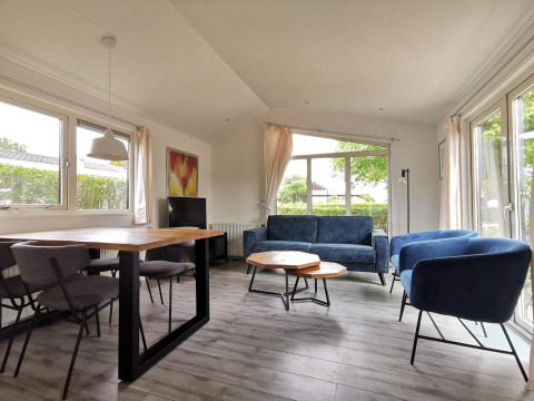 Sala luminosa en Chalet Basic de De Woudhoeve, Países Bajos, con mobiliario moderno y vistas al jardín.