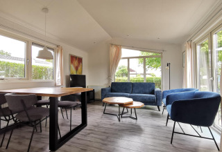Sala luminosa en Chalet Basic de De Woudhoeve, Países Bajos, con mobiliario moderno y vistas al jardín.