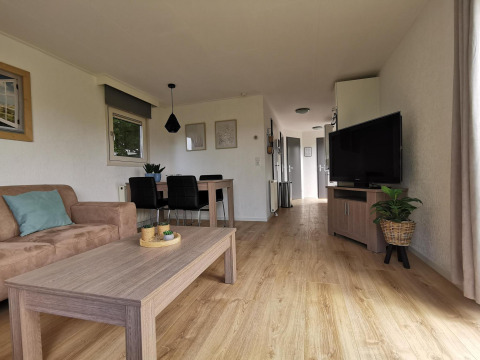 Sala de estar moderna y luminosa en Chalet Basic de De Woudhoeve, Países Bajos, con muebles de madera y TV.