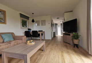 Sala de estar moderna y luminosa en Chalet Basic de De Woudhoeve, Países Bajos, con muebles de madera y TV.