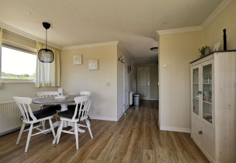 Spisestue i Chalet Basic hos De Woudhoeve, Holland, med lyse vægge, træmøbler og vitrineskab.