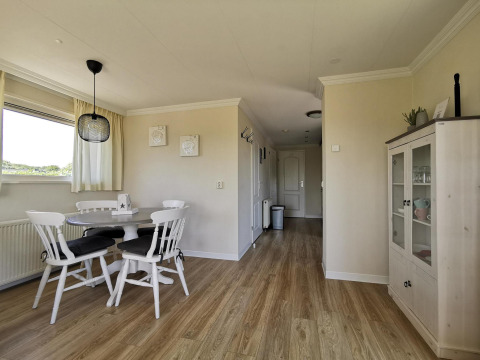 Comedor en Chalet Basic en De Woudhoeve, Países Bajos, con piso de madera y muebles blancos clásicos.